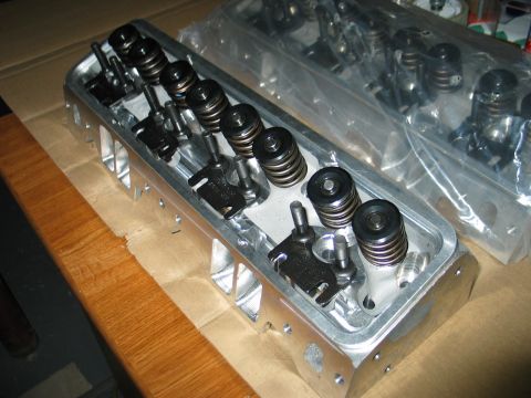 1981 Chevrolet Corvette - Engine cylinder heads shown on a wooden surface, some are still in plastic packaging.
