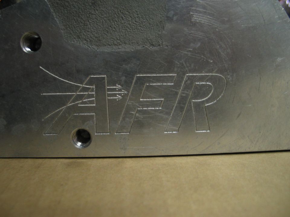 Close-up of an aluminum part with AFR logo and airflow graphics etched into it