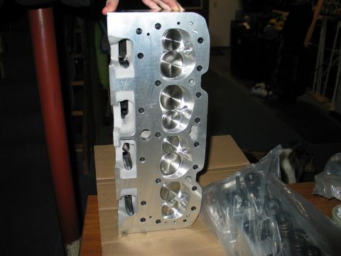 1981 Chevrolet Corvette - An aluminum engine cylinder head, likely for a performance application, is held up for inspection.