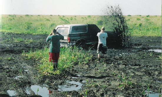 1992 Ford Bronco stuck in mud with two people watching