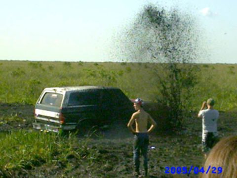 1992 Ford Bronco - A 1992 Ford Bronco is stuck in the mud with a splash of mud in the air.