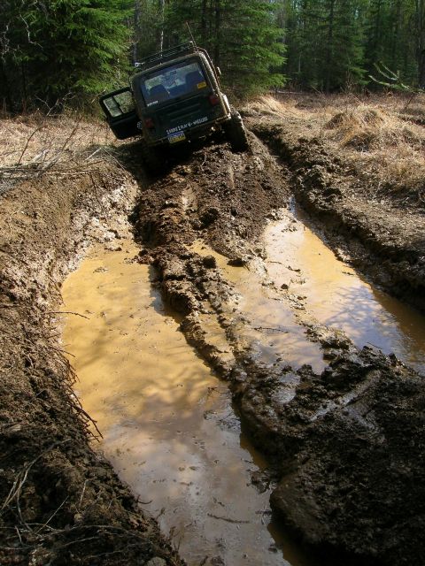 2003 Jeep TJ - 2003 Jeep TJ navigating a challenging muddy trail with its door open.
