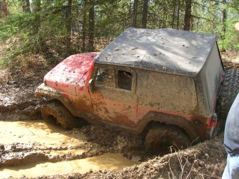 2003 Jeep TJ - A red Jeep Wrangler is stuck in a mud pit during an off-road excursion.