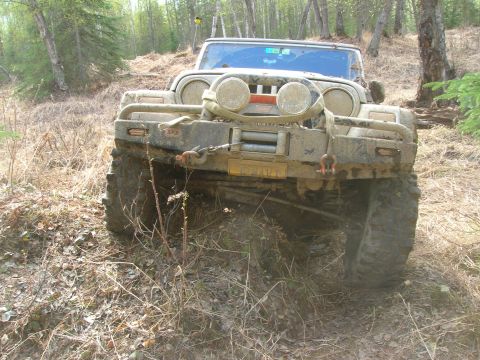 2003 Jeep TJ - A muddy 2003 Jeep Wrangler navigates an off-road trail.