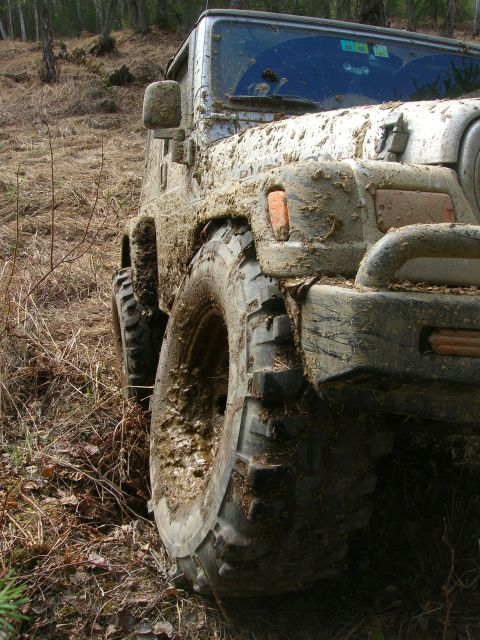 2003 Jeep TJ - A muddy 2003 Jeep TJ navigates off-road terrain.