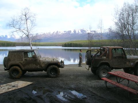 2003 Jeep TJ - Two Jeep Wranglers are parked near a lake with a mountainous backdrop.