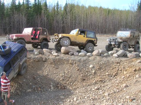 2003 Jeep TJ - Multiple Jeep Wranglers, including a yellow TJ, tackle a challenging rocky terrain during an off-road excursion.