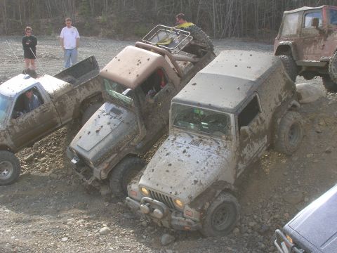 2003 Jeep TJ - Several off-road vehicles are stuck in the mud on a rocky trail.