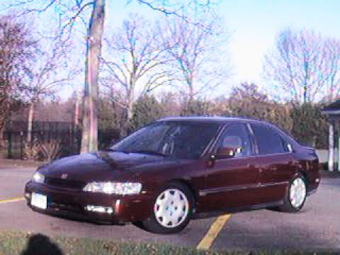 1993 Ford Bronco - Three-quarter front view of a dark burgundy four-door Honda Accord sedan parked in a lot on a bare-tree winter day, headlights on. It wears…