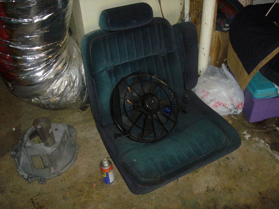 Car seat with a fan on it, next to a metal part and a can of spray