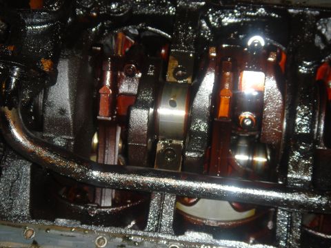 1986 Ford Mustang - Close-up view of an engine's internal components, showing the crankshaft and connecting rods coated in oil.