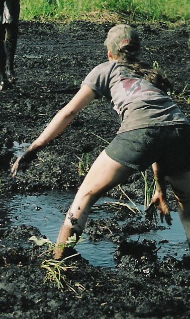 1992 Ford Bronco - Two people are covered in mud while navigating a muddy field with some water.