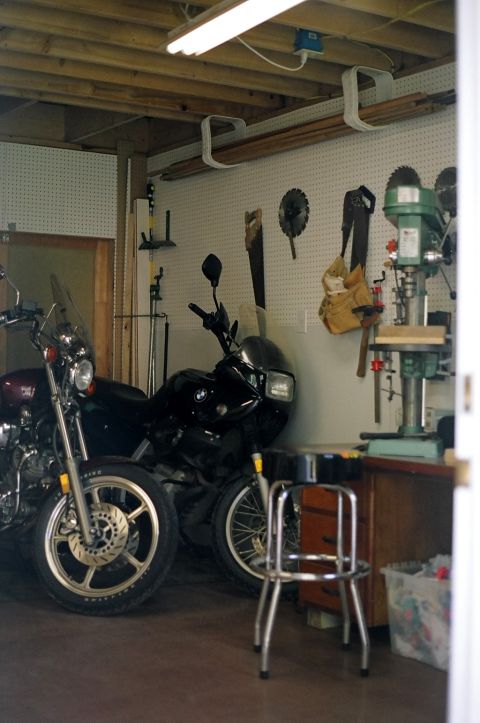 1976 Ford F-150 - A workshop scene two motorcycles parked indoors, with various tools and equipment visible on the walls and workbench.