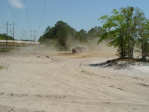 1994 Ford Bronco - A vehicle navigates a dusty, off-road course under a clear blue sky.