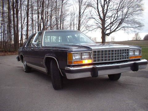 1984 Ford Crown Victoria LTD - This sedan features a prominent chrome grille and distinctive quad headlights, suggesting a specific model year.