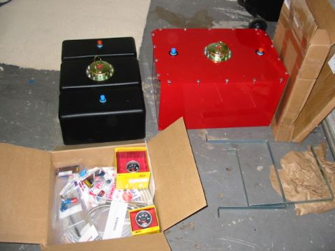 1985 Ford LTD Crown Victoria - Various automotive parts including fuel tanks and gauges are laid out on a concrete floor.