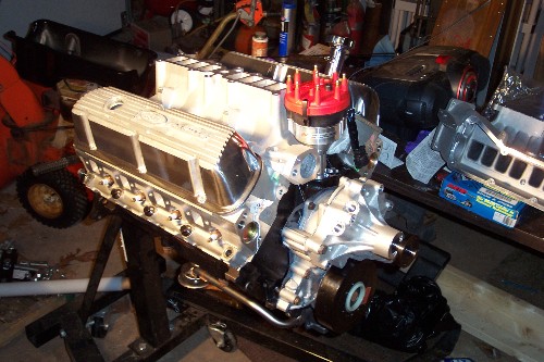 Rebuilt V8 engine with aluminum heads and red-cap distributor on an engine stand in a garage