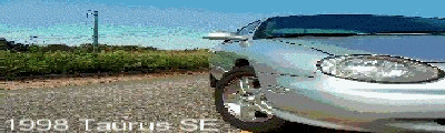 1998 Ford Taurus - Silver 1998 Ford Taurus SE parked on a gravel lot with a body of water in the background.