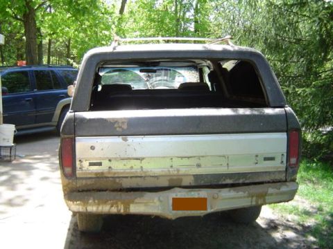 1979 Ford Bronco - Mud-covered 1978 Ford Bronco seen from the rear, with another vehicle in the background.