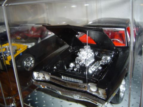 1979 Ford Bronco - A black model car with an exposed chrome engine and red interior is displayed, with other models visible in the background.
