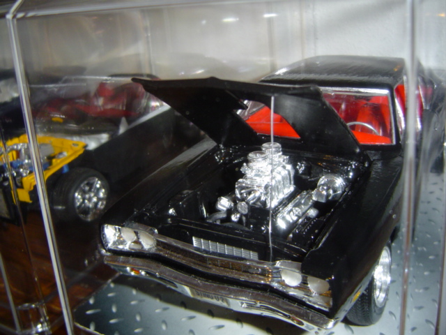 Black model car with chrome engine and red interior, hood open, front view