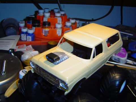 1979 Ford Bronco - Unfinished model kit of a Ford Bronco with a prominent supercharger on the hood, on a workbench.