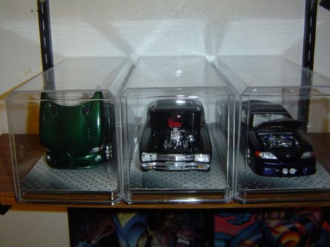 1979 Ford Bronco - Three detailed model vehicles are showcased in individual clear display cases on a shelf.