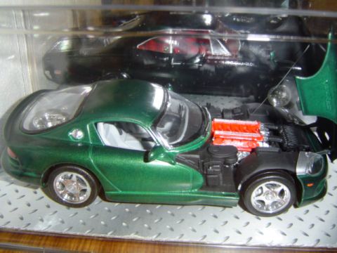 1979 Ford Bronco - A green sports car model is displayed with its hood open, revealing the engine, with another car in the background.