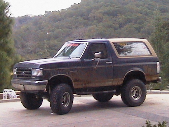 Dark blue and tan 1991 Ford Bronco, lifted, 3/4 front view
