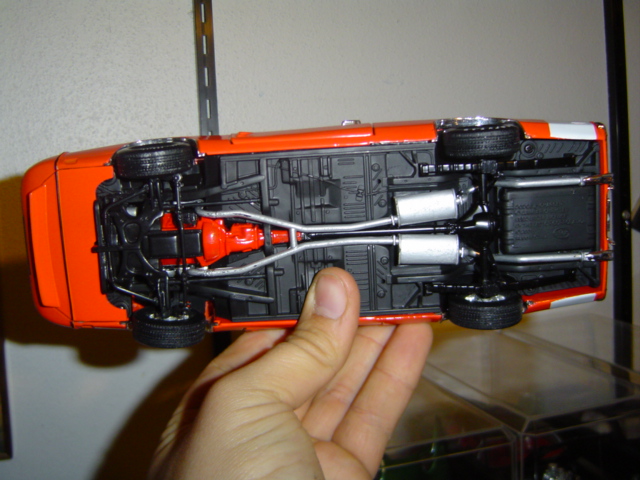 Orange model car upside down showing chassis, exhaust, and engine detail