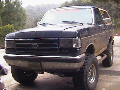1991 Ford Bronco - This lifted Ford Bronco is shown from a low front three-quarter angle, highlighting its off-road modifications.