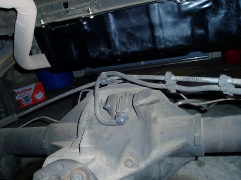 1990 Ford Bronco - Close-up view of a vehicle's rear axle assembly and fuel tank, with some plumbing and exhaust components visible.