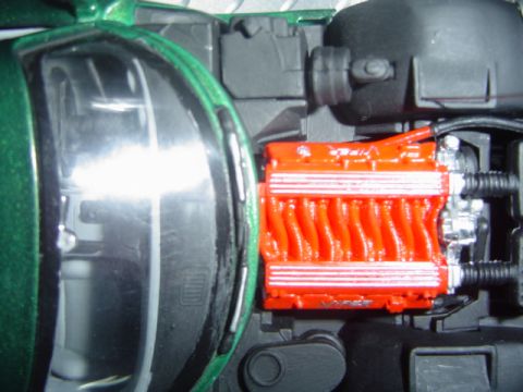 1979 Ford Bronco - Close-up view of an orange V10 engine, likely from a model car, situated within a green vehicle's engine compartment.