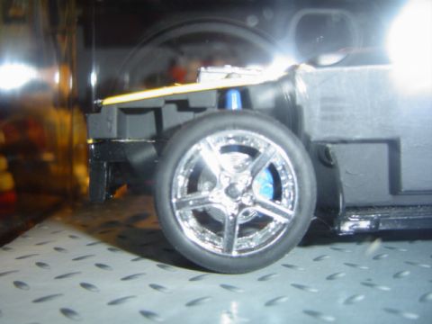 1979 Ford Bronco - A detailed view of a toy vehicle's chrome wheel and suspension system.