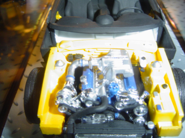Yellow model car engine bay with chrome and blue engine parts