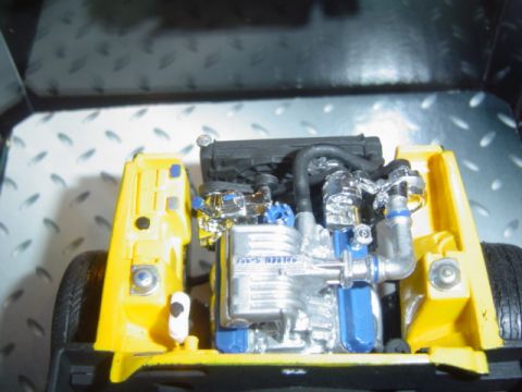 1979 Ford Bronco - Detailed engine bay of a yellow toy truck, chrome and blue engine components.