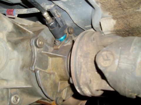 1990 Ford Bronco - Close-up underside view of a drivetrain component, likely a transfer case or transmission tail housing, with a two-wire electrical connecto…