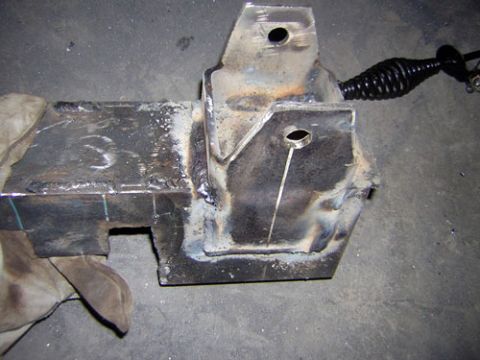 1995 Ford Bronco - A close-up view of a custom-welded metal bracket, possibly for a vehicle modification, with a coiled spring-like component attached.