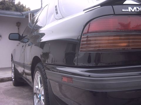 1989 Mazda MX-6 - Rear view of a black 1989 Mazda MX-6, highlighting its distinctive taillight design and spoiler.