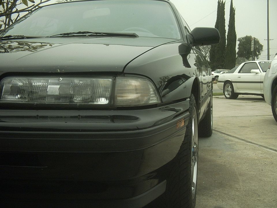 Close-up of black Mazda MX-6 front corner headlight and bumper