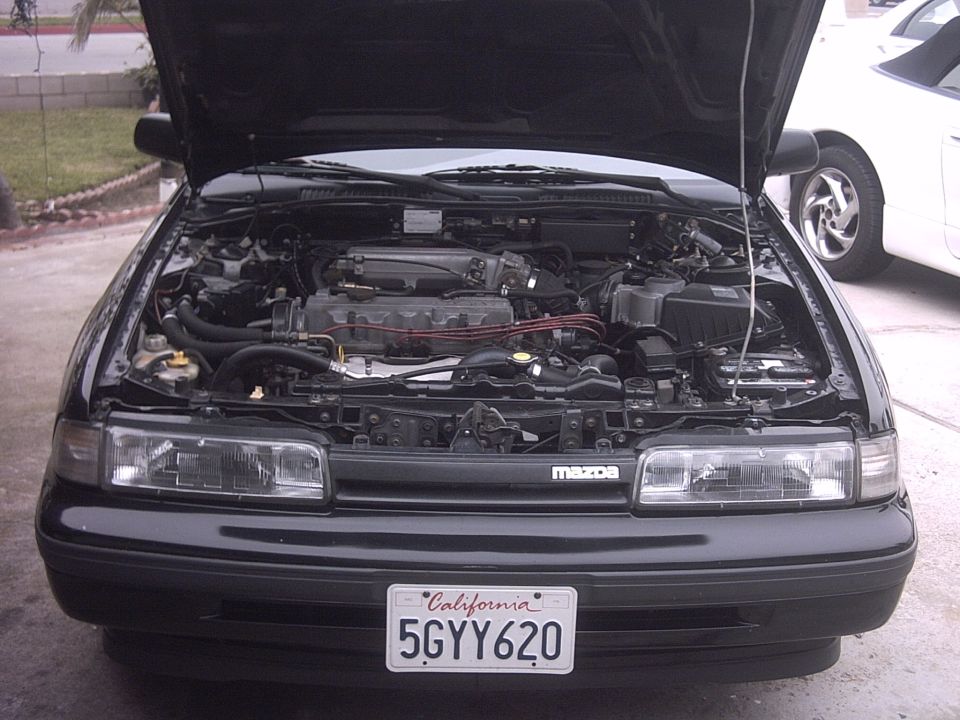 Black Mazda coupe front, hood up showing engine, CA plate 5GYY620