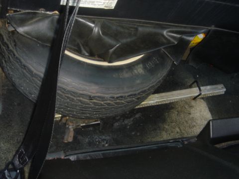 1975 Ford Ranchero - The spare tire and jack are secured in the vehicle's storage compartment.