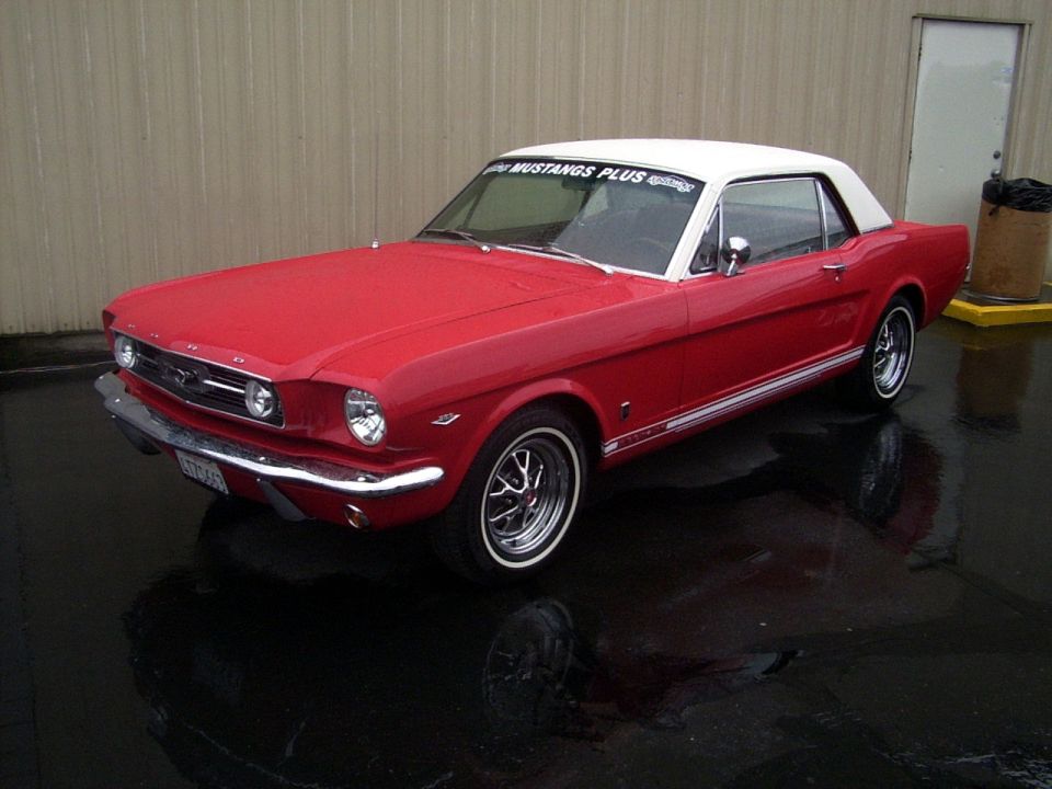 Red 1965 Ford Mustang coupe with a white vinyl roof. It has chrome trim and wheels