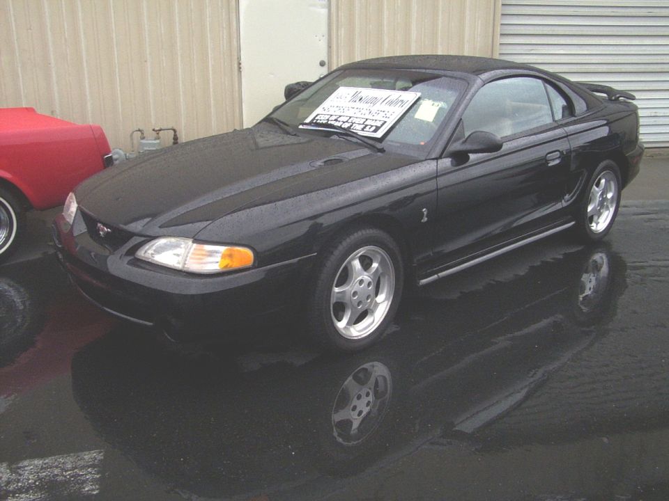 Black 2002 Ford Mustang coupe with spoiler and aftermarket wheels