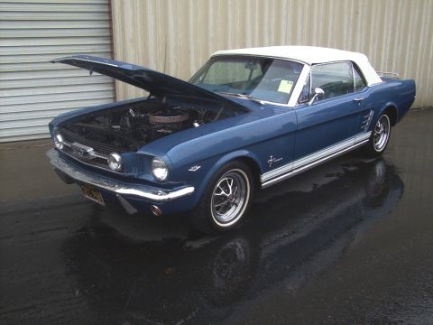 2002 Ford Mustang - A blue 1965 Ford Mustang convertible is parked outside with its hood open, showing the engine bay.
