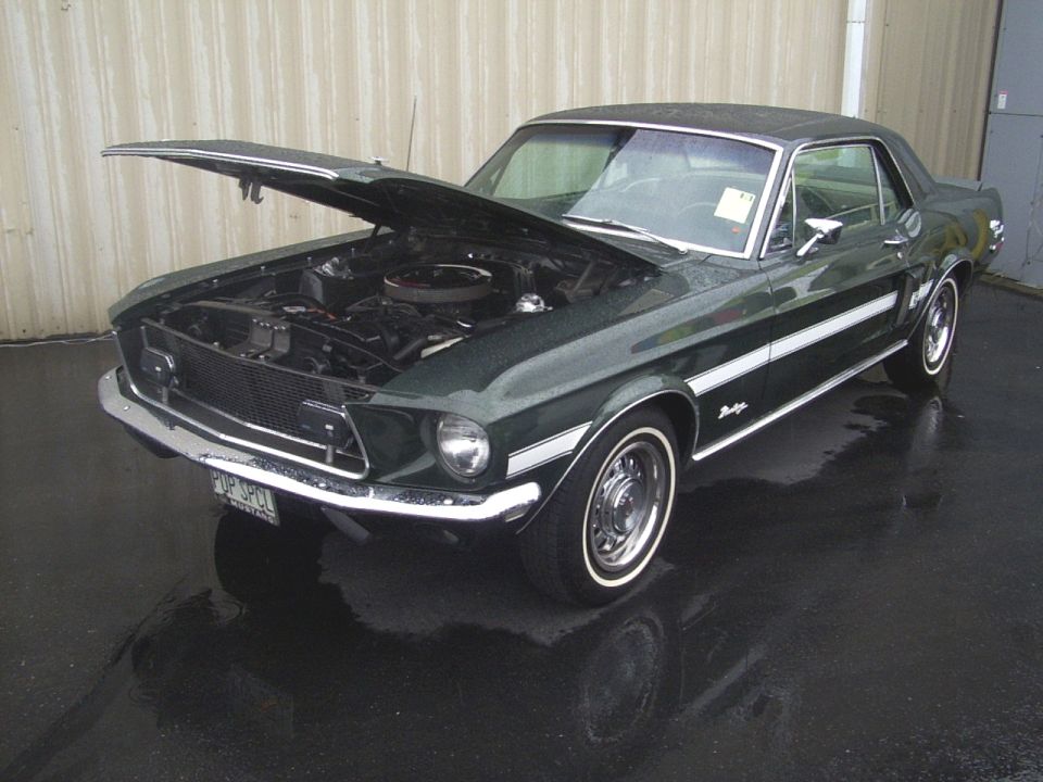Dark green 1967-1968 Ford Mustang coupe with hood open, showing engine
