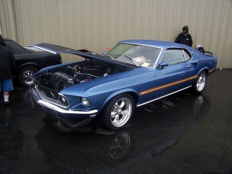 2002 Ford Mustang - A blue classic Ford Mustang is displayed with its hood open, parked next to another vehicle.