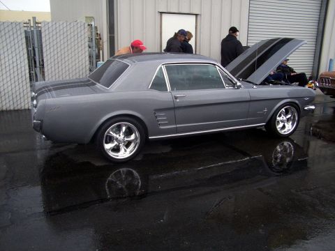 2002 Ford Mustang - A classic gray Ford Mustang is parked outside with its hood open, reflecting in the wet pavement.