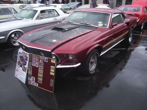 2002 Ford Mustang - A maroon 1969 Ford Mustang Mach 1 is displayed next to other classic cars on a wet day.