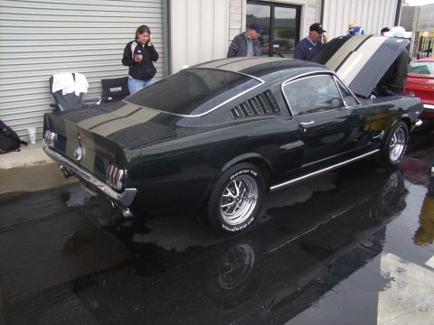 2002 Ford Mustang - A classic 1965 Ford Mustang is displayed with its hood open, reflecting on the wet ground.